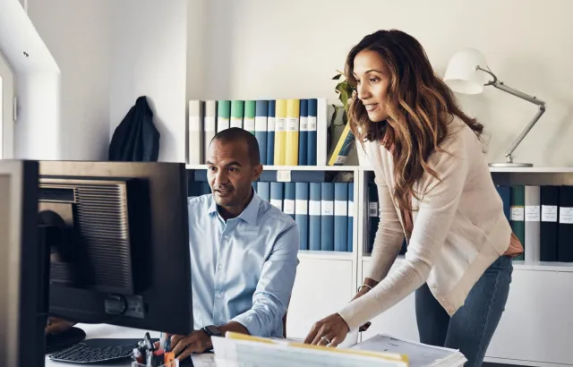 Woman and man excitedly looking at the computer monitor together in an office