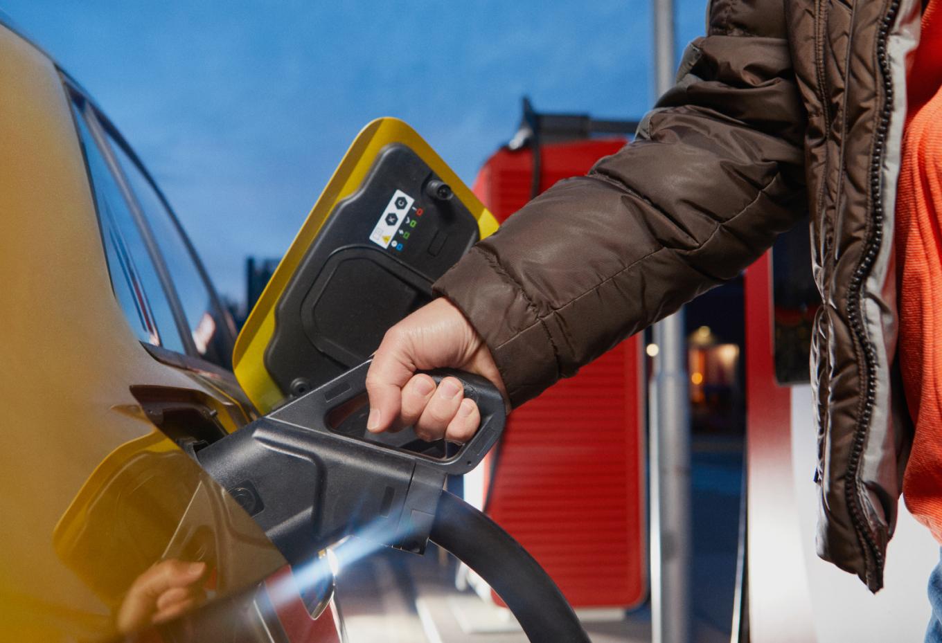 Persoon die het laadpistool in de auto steekt om deze elektrisch op te laden