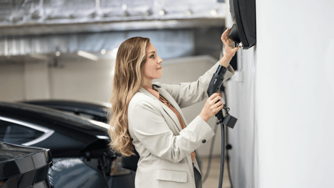 Vrouw koppelt haar lader om elektrisch te laden in een parkeergarage