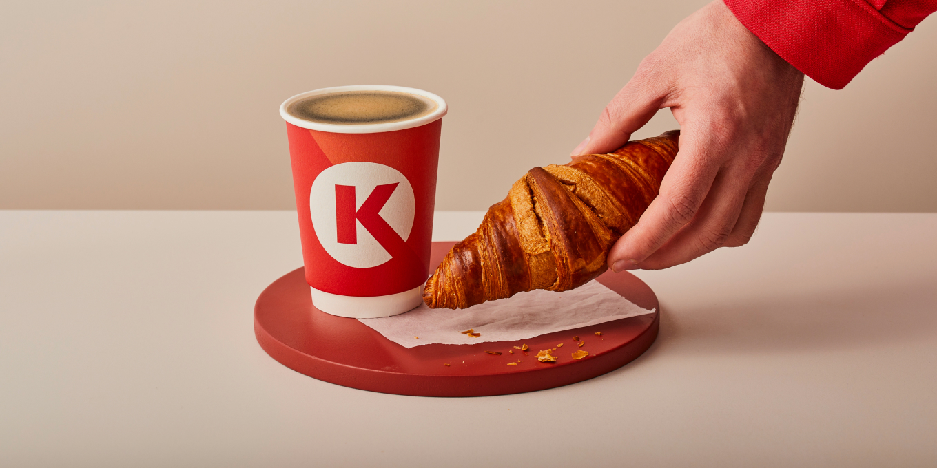 Circle K koffie met een croissant die wordt gepakt door een hand