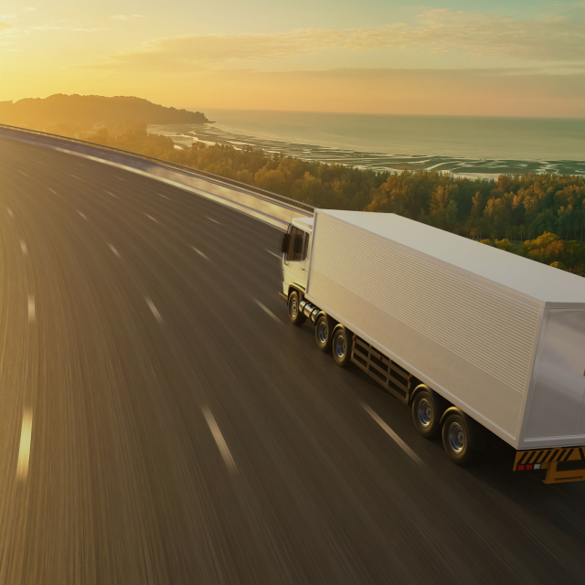 Rijdende vrachtwagen op snelweg tijdens zonsondergang
