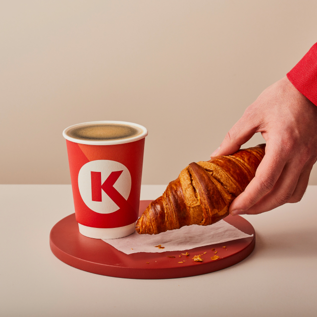 Circle K koffie met een croissant die wordt gepakt door een hand